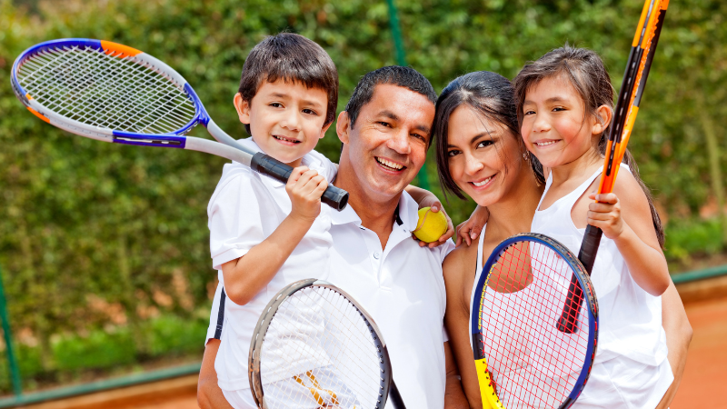 family holding tennis rackets smiling
