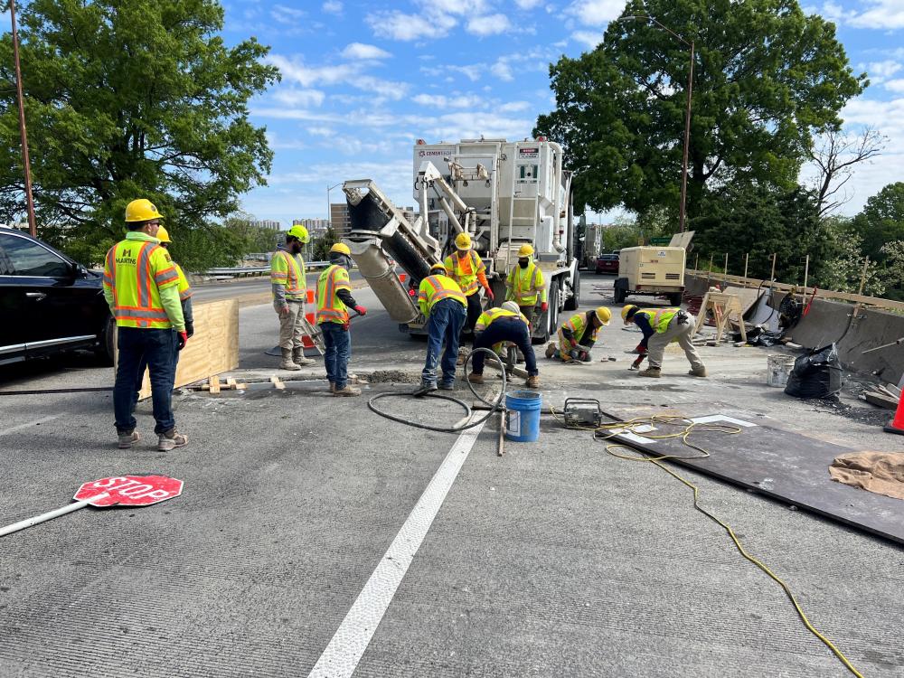 Construction crew works quickly to smooth out concrete being poured from a truck.