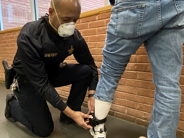 deputy places electronic monitor on ankle of client