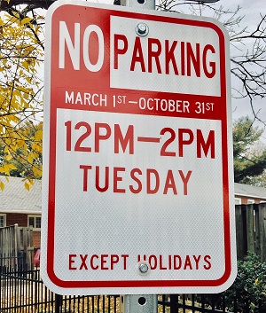 Red and white street sign, text reads: "No Parking, March 1-October 31, 12pm-2PM, Tuesday, Except Holidays