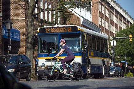 Person riding bicycle across King Street with DASH bus in background