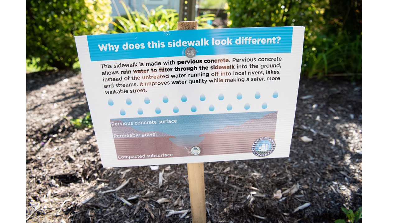 Sign with text that reads: Why does this sidewalk look diferent? This sidewalk is made with pervious concrete, which allows rain water to filter through the sidewalk into the ground, instead of the untreated water running off into local rivers, lakes, and streams. It improves water quality while making a safer, more walkable street. 