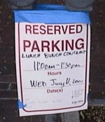 A photo of a red-and-white temporary reserved parking sign, which the City posts whenever residents reserve spaces for moved, wedding, funerals, and other events