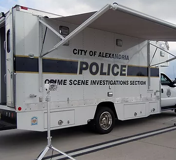 A van with an awning extended and the words "City of Alexandria Police Crime Scene Investigations Section" on the side
