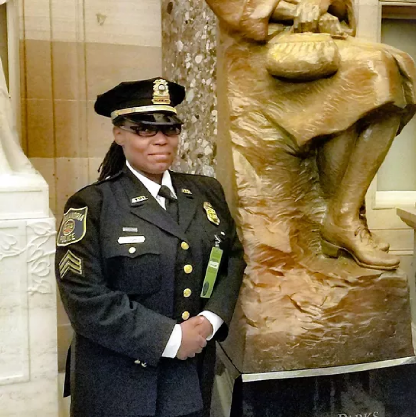 Hurley, wearing a dress uniform, poses beside a statue