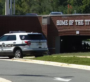 A Police SUV in front of a parking garage with the sign "HOME OF THE" indicating that it is a school