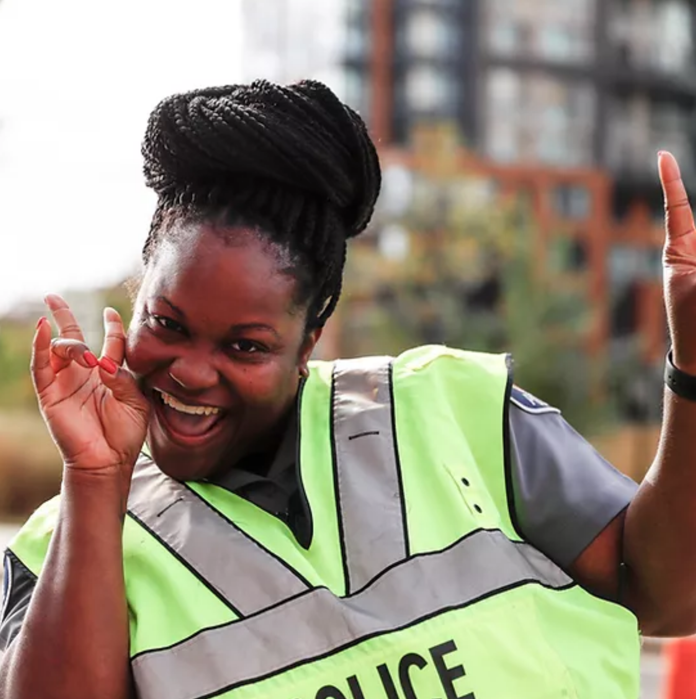 Shakita Warren wearing a high visibility vest and smiling, holding up both hands in 'peace signs'