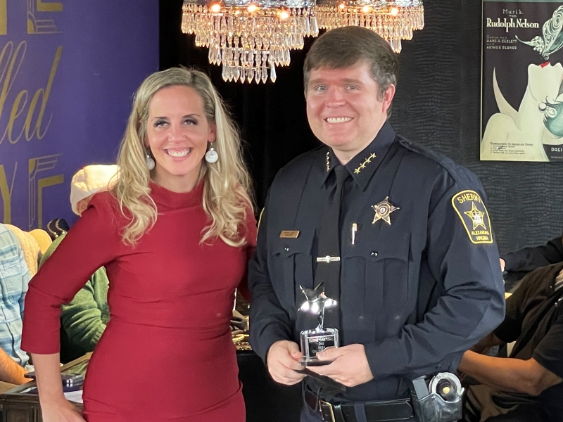 business person and sheriff holding a small trophy