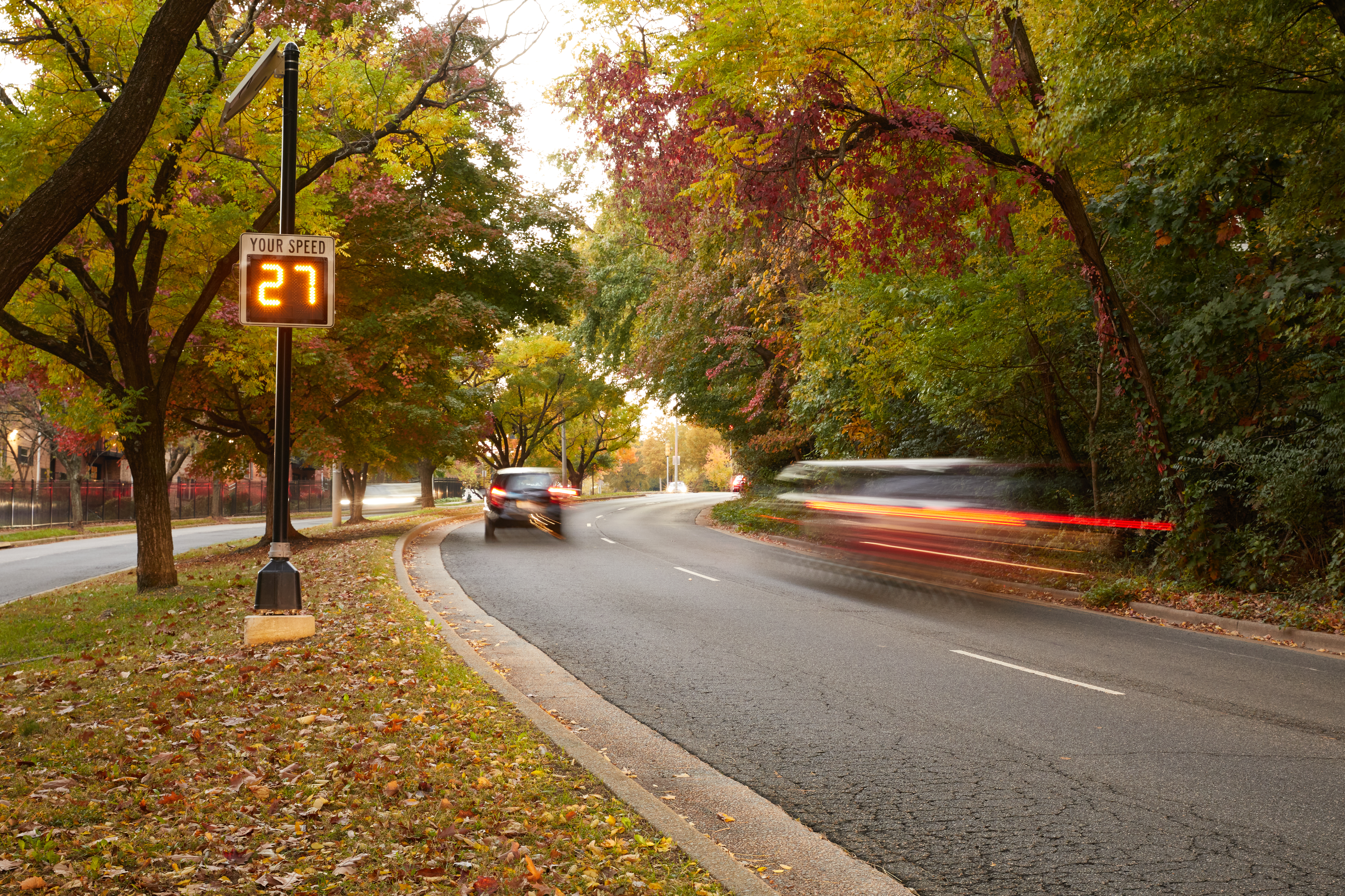 A photo showing a person driving past a speed radar sign