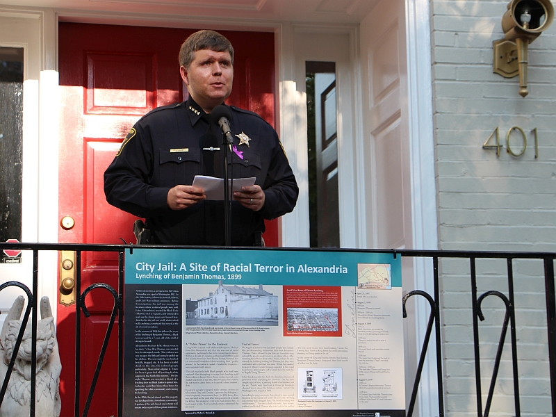 sheriff standing and giving remarks with a illustrated historic marker in front