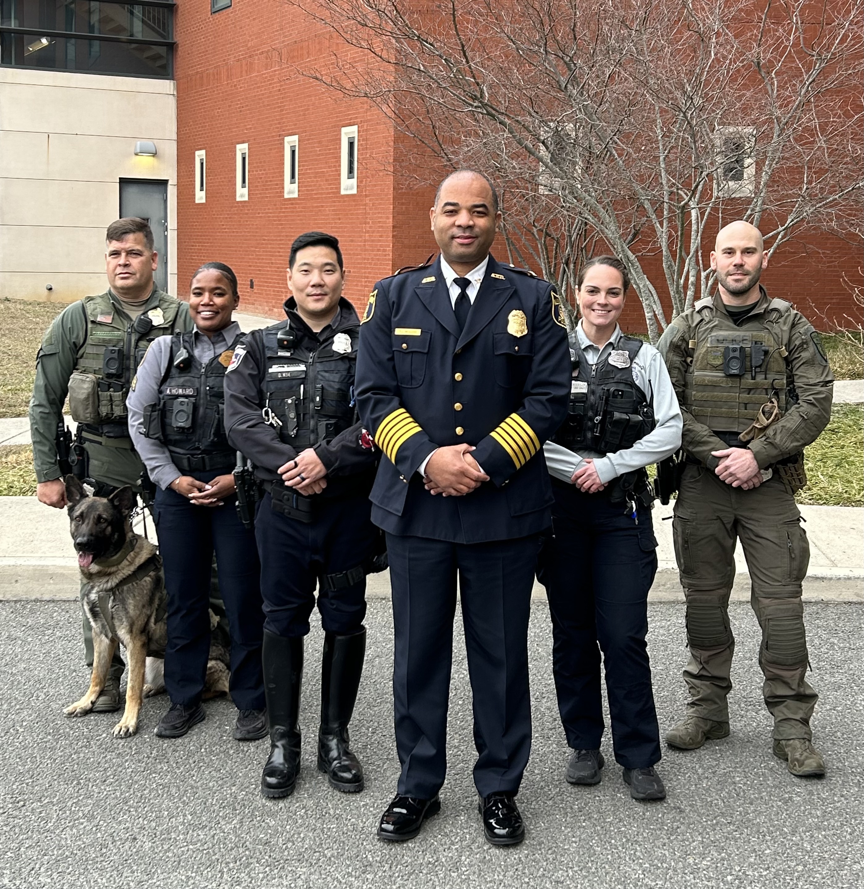 Chief of Police Tarrick McGuire and five other officers standing together in front of the Alexandria Police Department headquarters building.