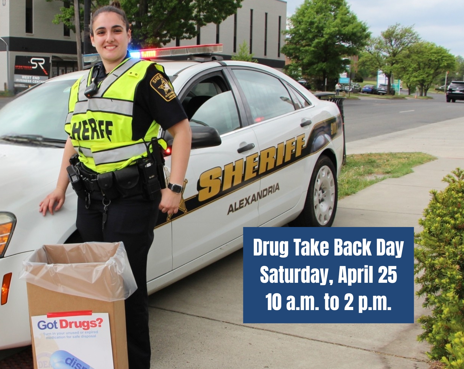 Deputy standing in front of Alexandria Sheriff cruiser with drug disposal box and message Drug Take Back Day, Saturday, April 25, 10 am to 2 pm