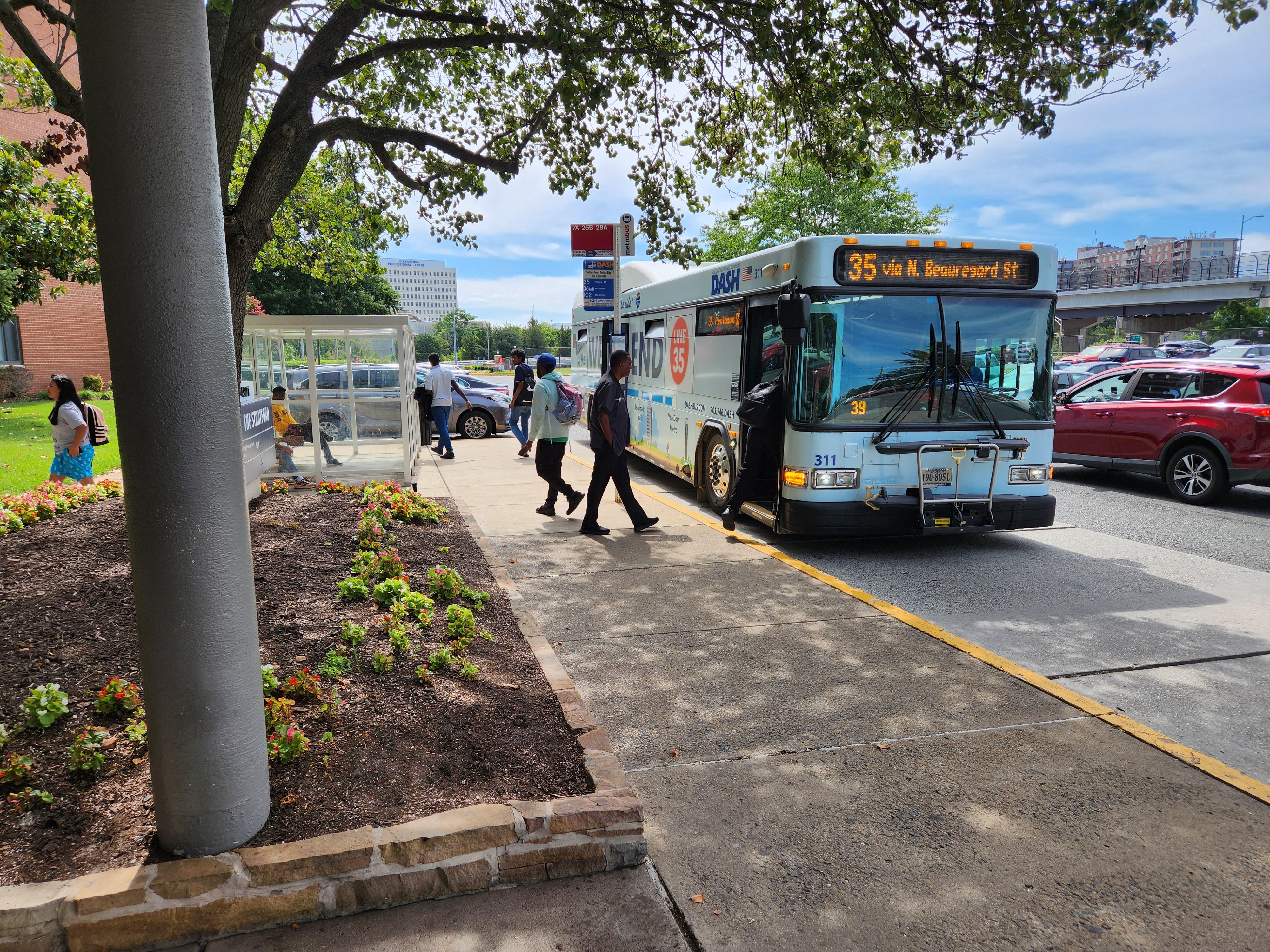 An image of a bus stopped with passengers getting on and off.