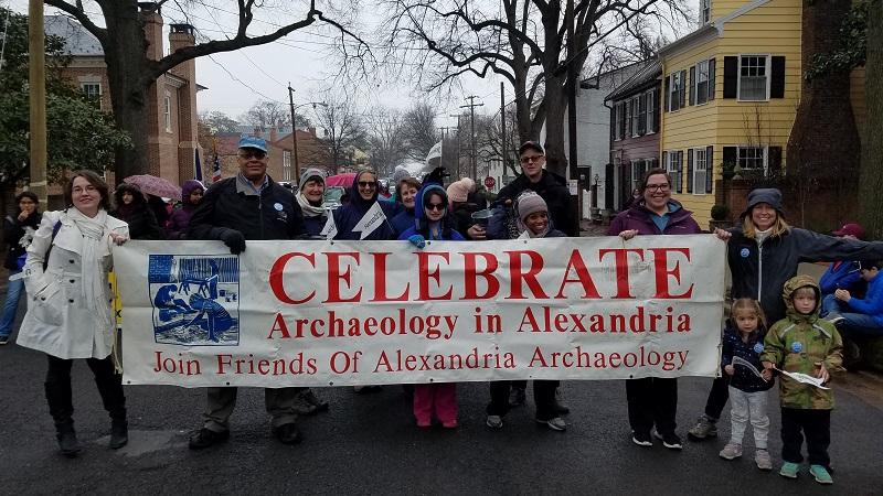 Friends of Alexandria Archaeology march in the George Washington Birthday Parade with Celebrate Archaeology in Alexandria banner