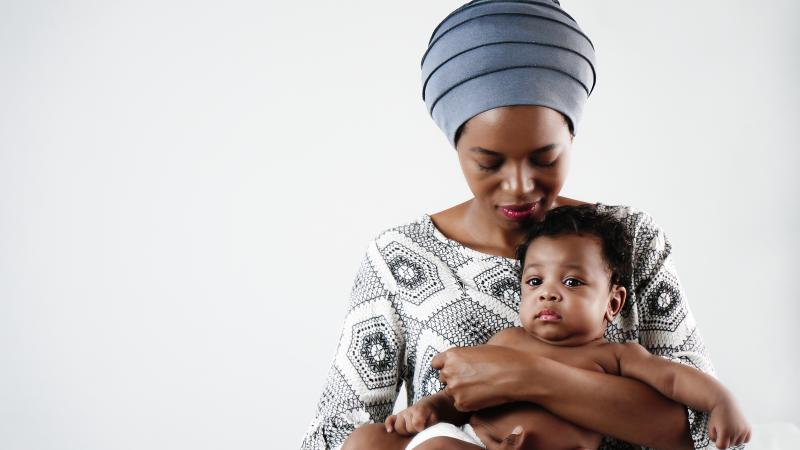 Woman in a head wrap holding a baby lovingly