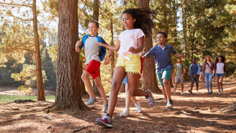 kids and adults running along trail in woods