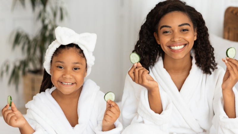 mom and daughter wearing robes and holding cucumber slices during spa day