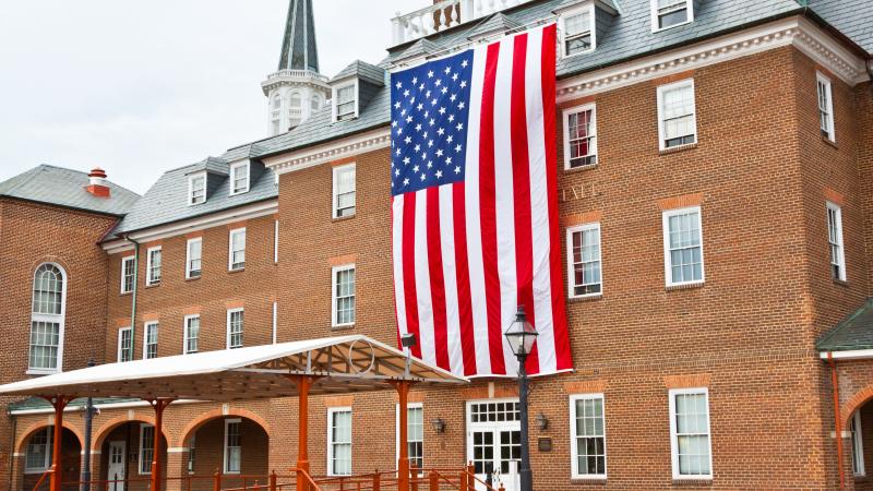 City Hall, a red brick building, with a very large American flag draped over the front entrance