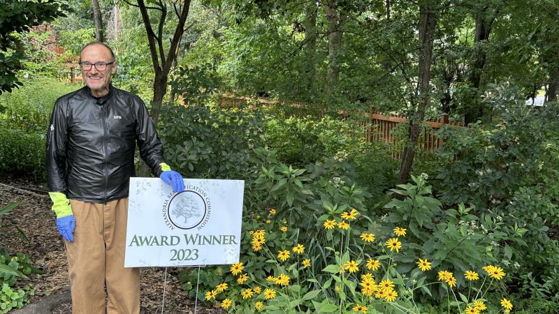 man standing in yard next to a sign that says award winner 2023