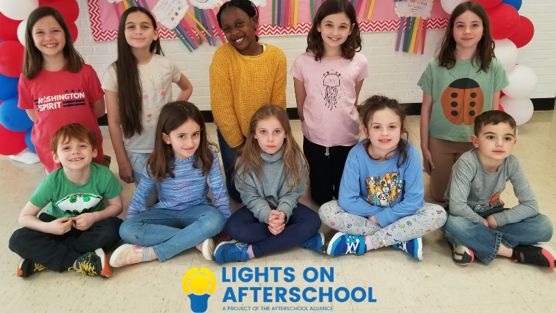 group of kids smiling at camera with lights on afterschool logo in bottom center