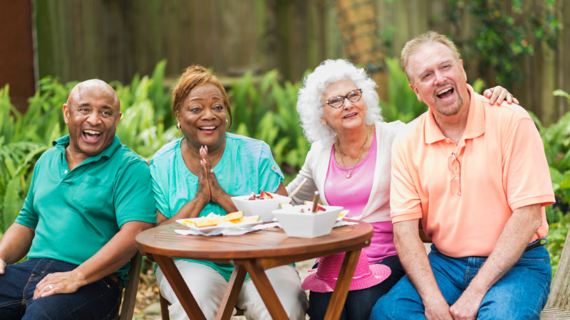 four seniors sitting outdoors smiling