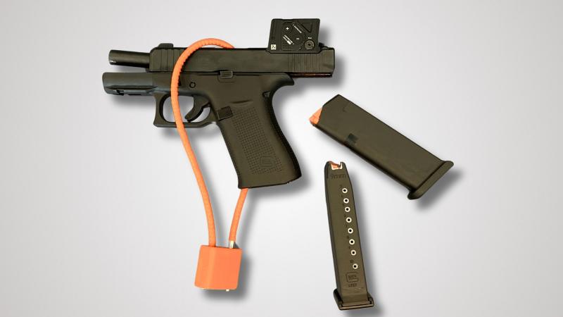 black handgun secured with orange cable lock and two magazines
