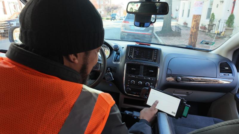 Paratransit operator inside vehicle with mobile device.