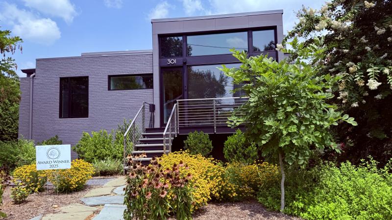 Image of a modern-looking house with huge windows and green yard and a sign that says Award Winner 2025