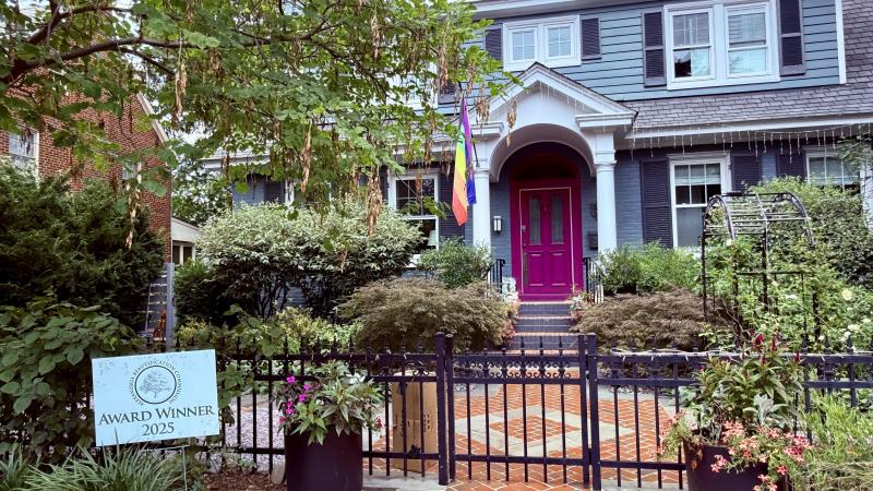Image of a blue house with a pink door and neat front yard with brick pathway
