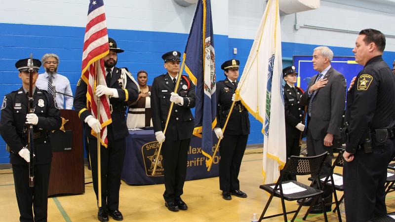 Public safety personnel in formal uniforms at a ceremony where the honor guard is holding flags