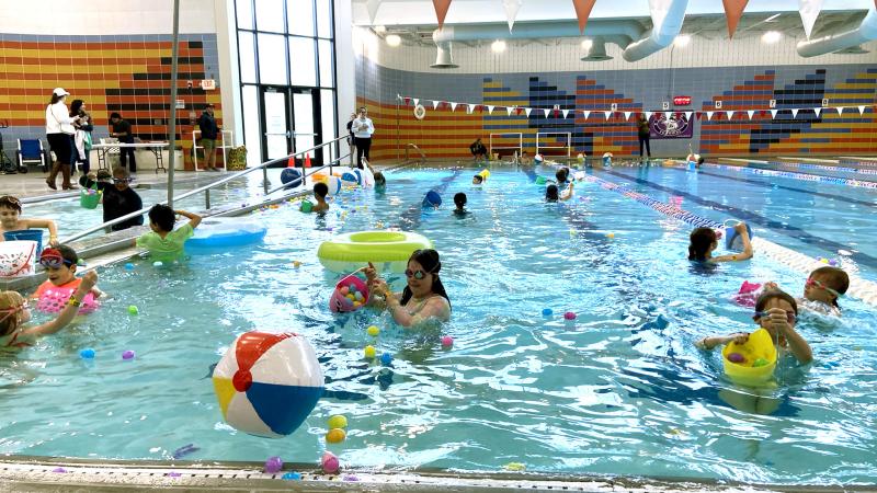 Image of the Chinquapin pool with kids hunting for plastic eggs and floaties on the surface of the water