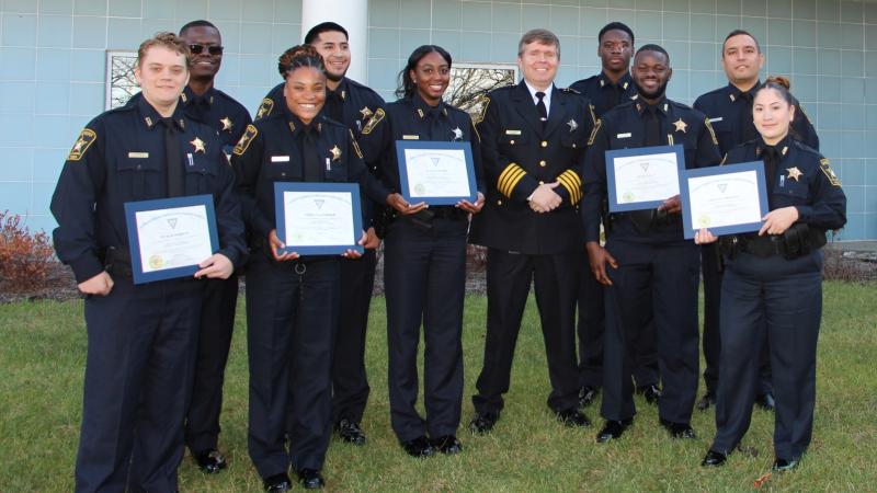 Nine deputies and sheriff, all wearing blue uniforms, standing together and smiling