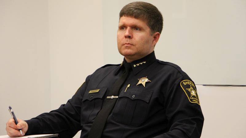 Sheriff in blue uniform sitting at a table and taking notes