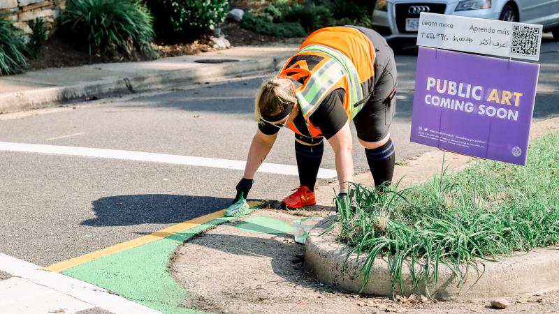 A woman draws with chalk on the road