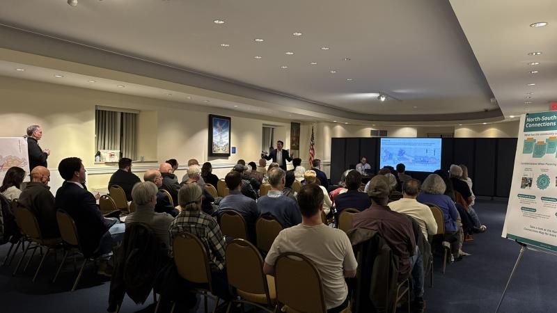 Image of meeting attendees sitting in the audience watching a presentation at the February 25th Community Meeting