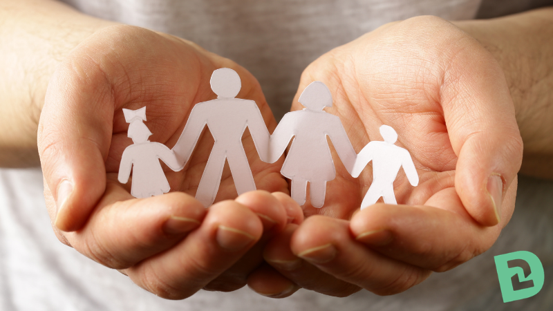 Hands cupped next to each other while holding a paper family cut out