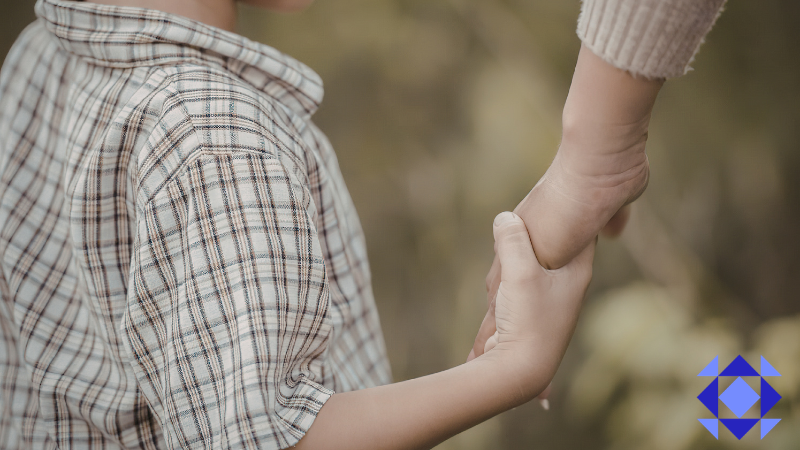 Only bottom of the child's nape to the right hand showing and child wearing a checkered collared shirt while holding a hand of an adult
