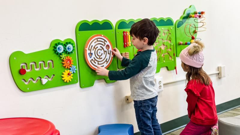 Two children playing with an interactive toy on the wall