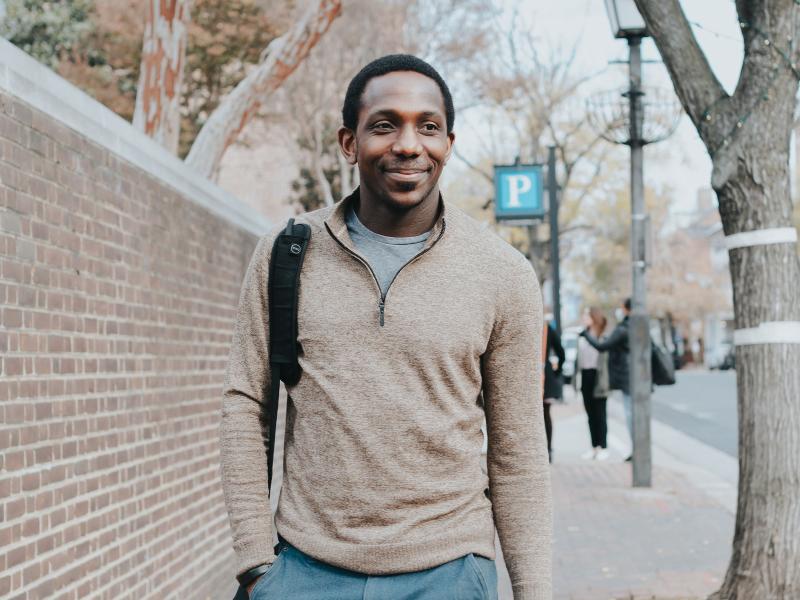 A photo of a commuter with a backpack and tote bag walking down King Street