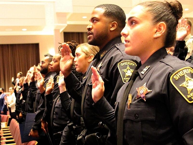 deputies in uniform holding their right hands up to take an oath