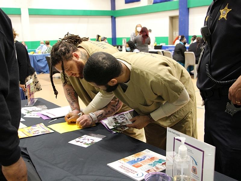 two inmates signing up for information from a resource fair exhibitor