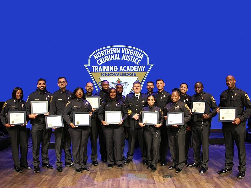 15 deputies holding certificates at graduation ceremony with sheriff in the center