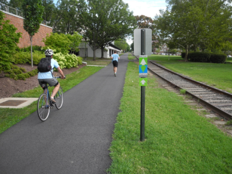 A cyclist and a runner travel along the Mount Vernon Trail in Old Town