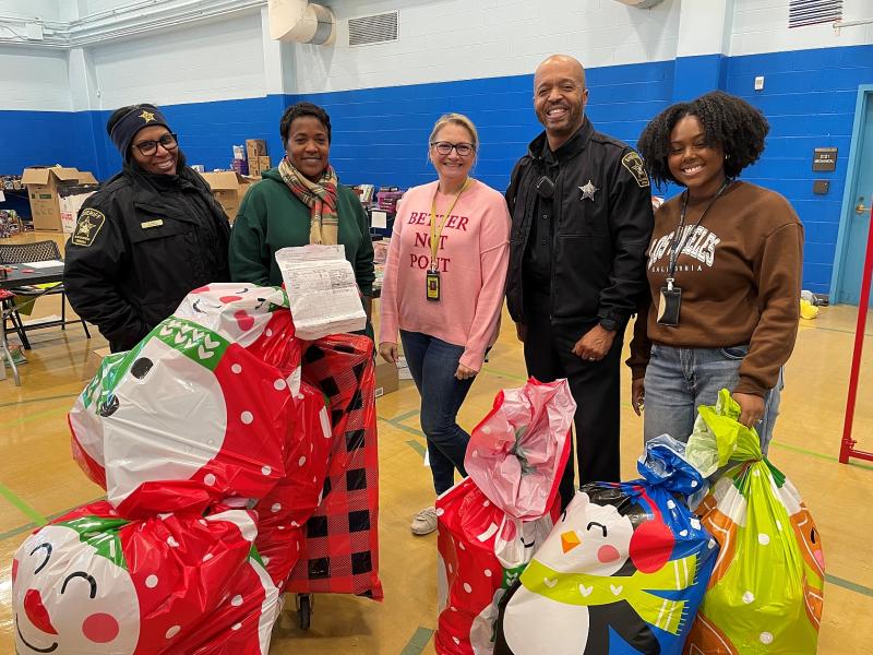 Two deputies and three civilians with bags of Christmas gifts around them