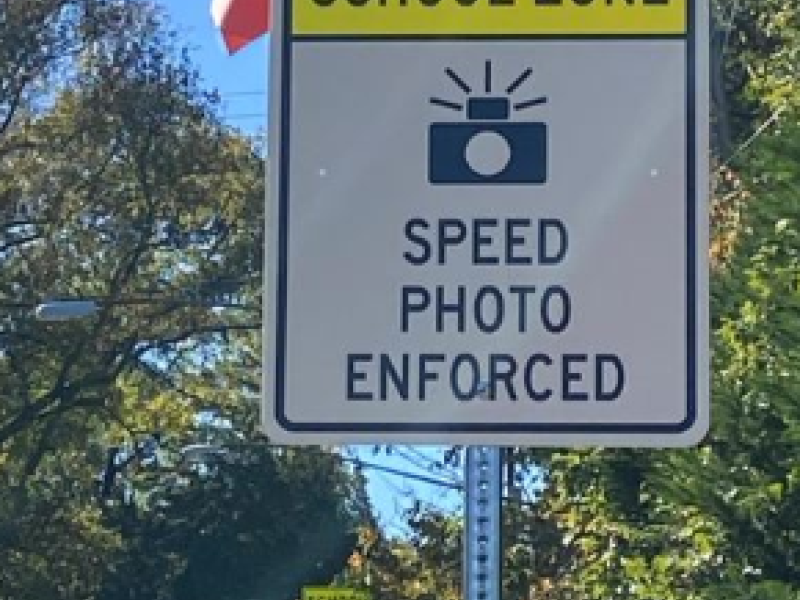 A road sign showing a camera with text saying Spped Photo Camera Enforce.