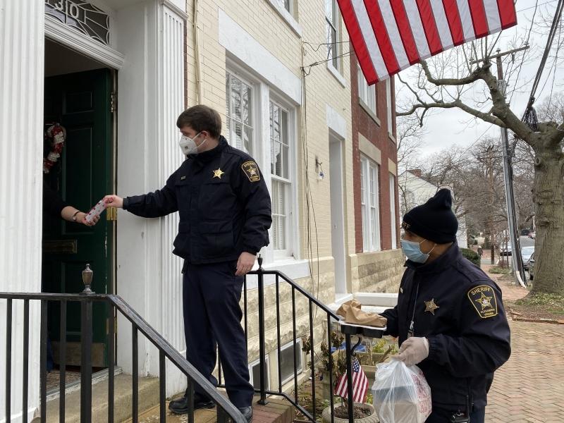 deputies at a door delivering a meal to a resident