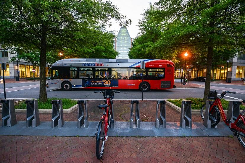 A photo of a Metrobus parked in front of a Capital Bikeshare corral in the Caryle neighborhood of Alexandria