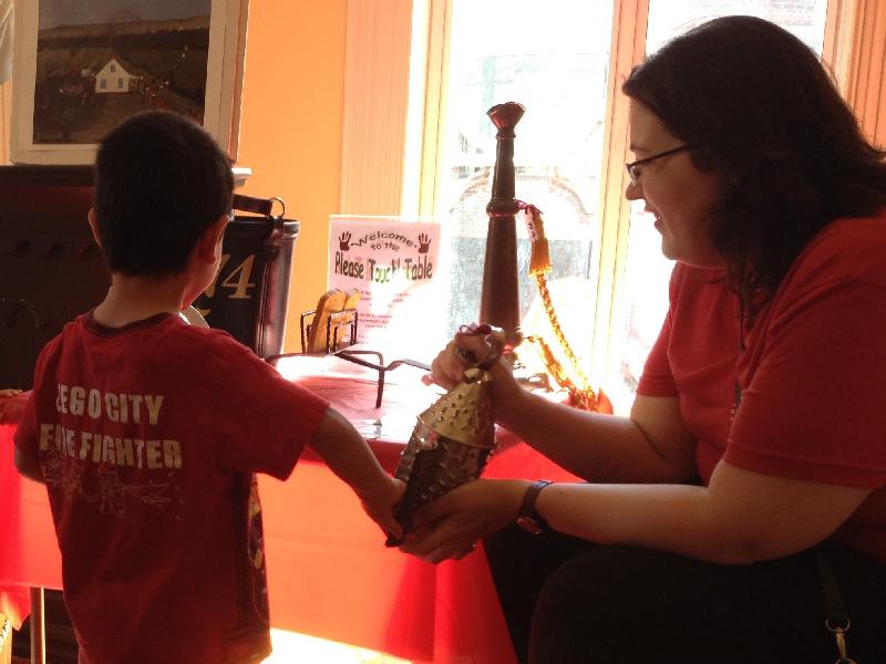 A child touches a tin lantern held by a museum staff member.