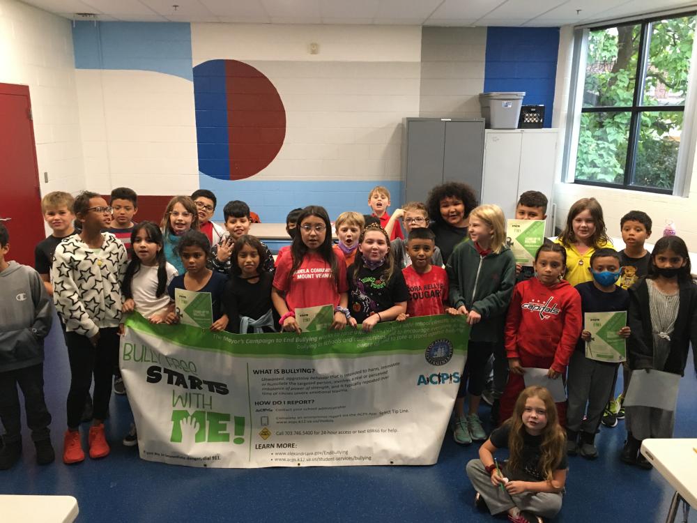 Elementary school children pose with a banner after seeing an October Bullying Prevention Month presentation 