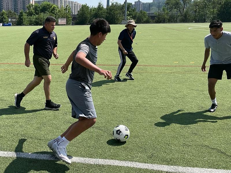deputy in summer uniform playing soccer with teens